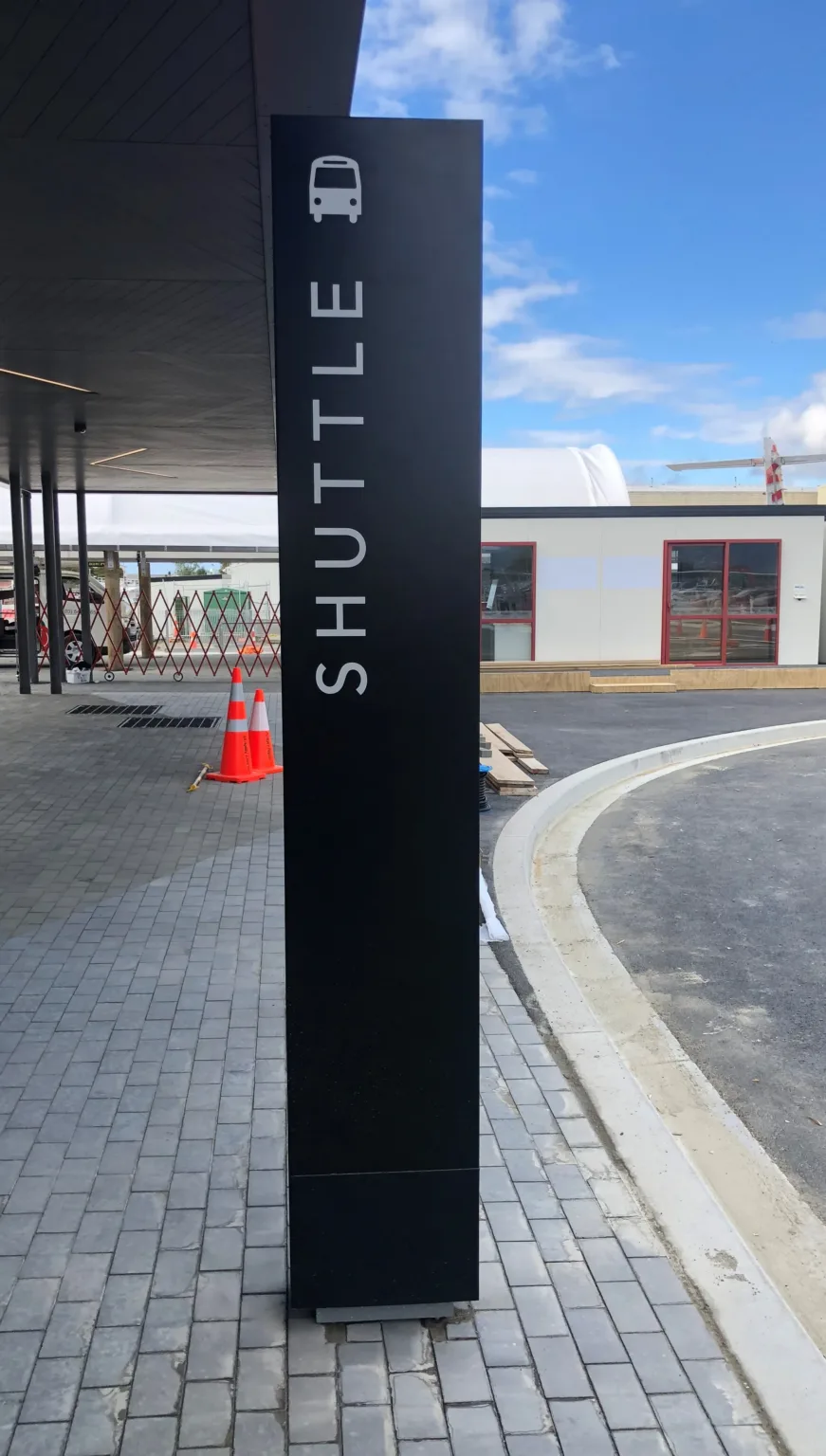 Small black plinth with white acrylic lettering reading "shuttle" and a bus icon